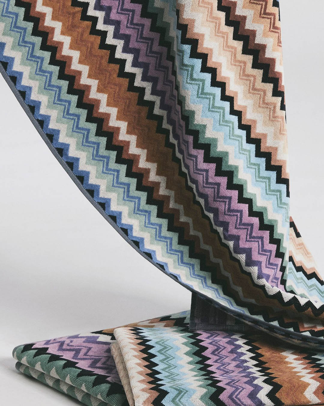 Colourful chevron zigzag patterned upholstery fabric draped and folded, pastel and earth-tone swatches