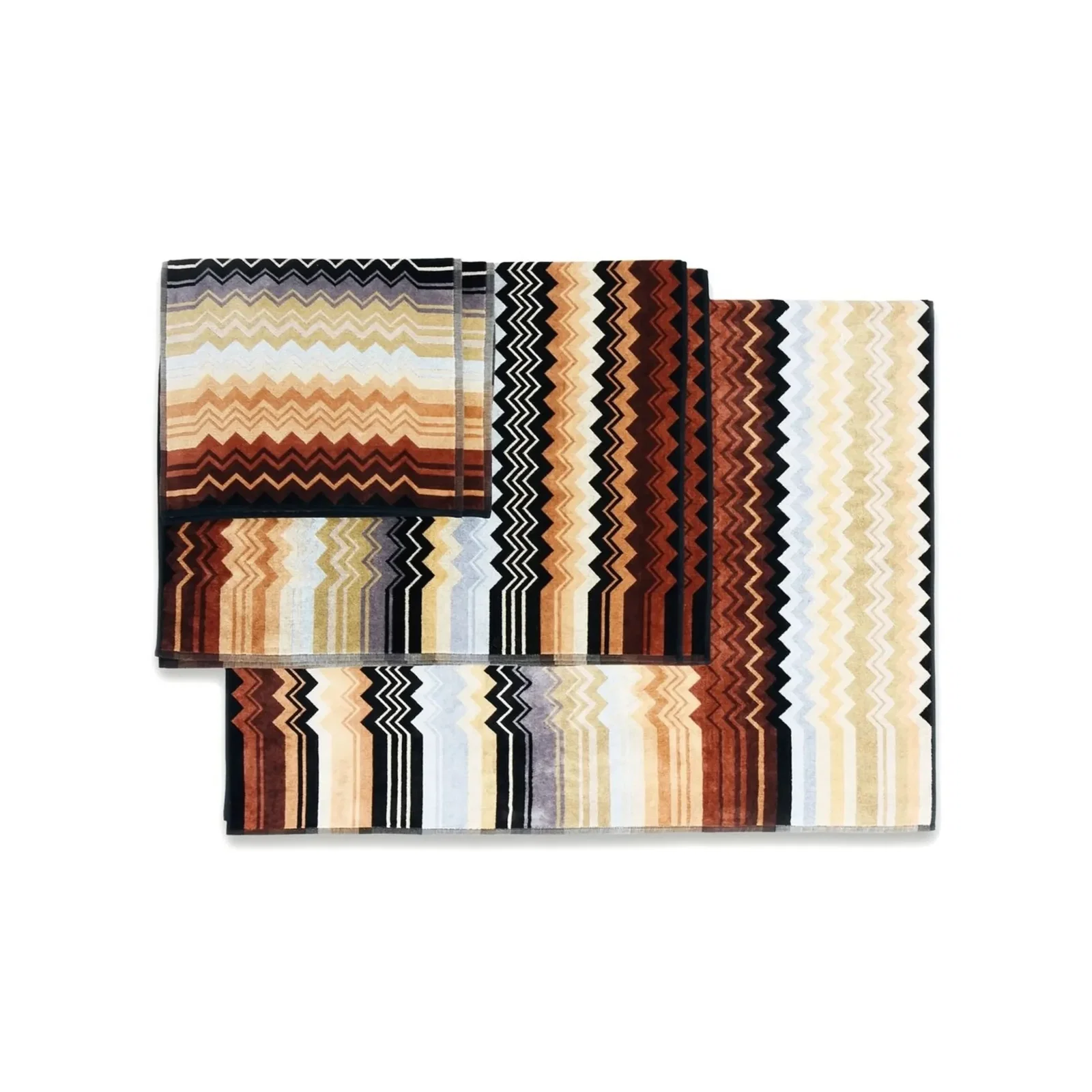 Folded towels with multicolour zigzag chevron stripes in warm browns, beige, cream and black on white background