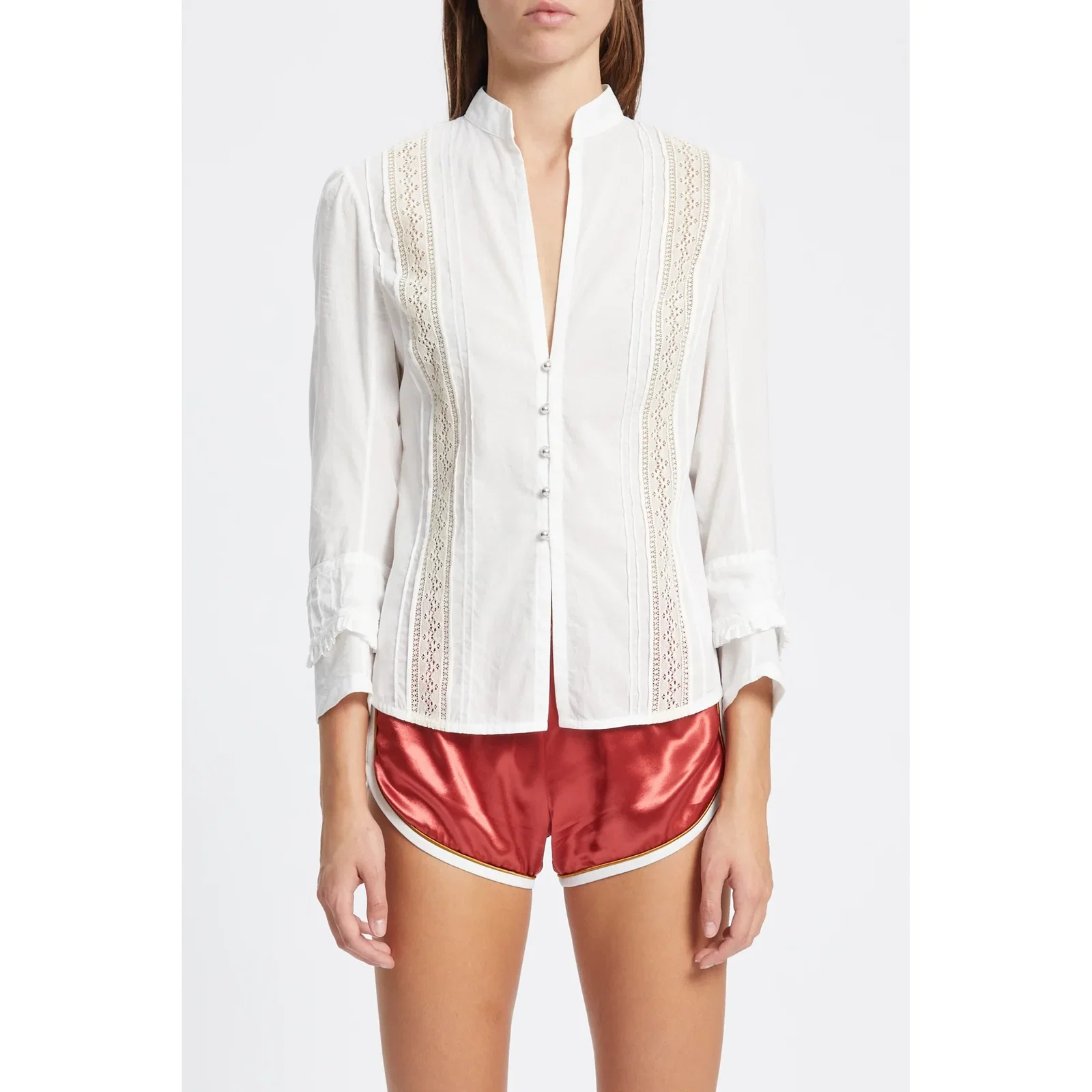 Woman wearing white lace-trimmed button-front blouse with mandarin collar and red satin athletic-style shorts