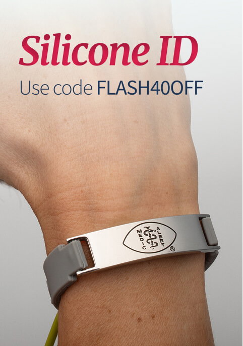 Close-up of a person's wrist wearing a sleek medical ID bracelet featuring a gray silicone band and a rectangular, polished silver tag. The silver tag has an engraved Caduceus logo. Dark red text in the top corner reads 'Silicone ID. Use code FLASH40OFF'.