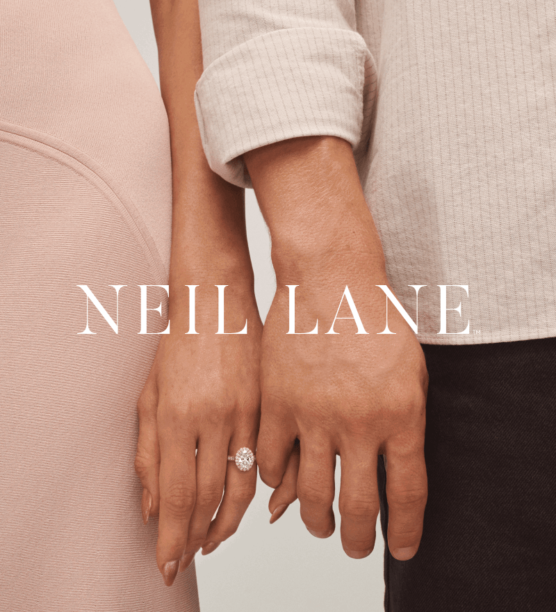 Man and woman holding hands. Woman wearing large oval cut engagement ring. Overlay of Neil Lane logo.
