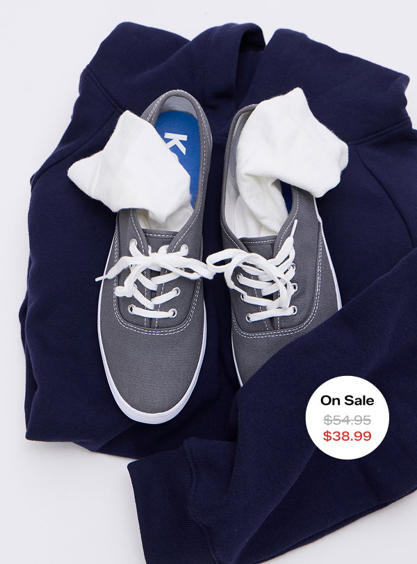 An overhead view of the Keds Champion Canvas Lace-Up in gray set on a navy sweatshirt. The style was $54.95 and is on sale for $38.99 for a limited time.