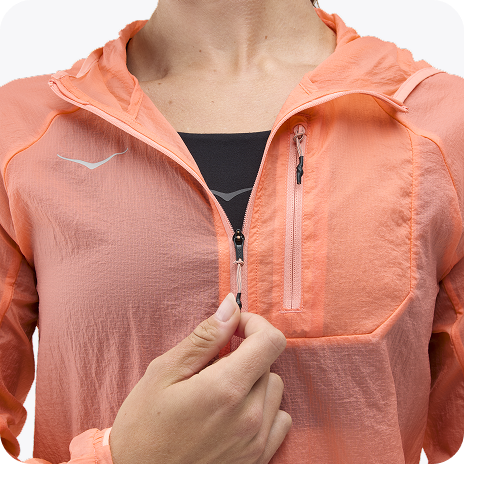 Block of three images: one image shows the chest of a woman wearing an orange windbreaker while holding the windbreaker zip with one hand; one image shows the side view of a pink sock with dark pink details; one image shows a woman crouching while tying her shoe, with buildings and a blue sky in the background.