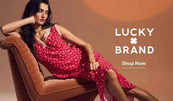 Image of a woman in a printed dress sitting in a chair. Lucky Brand logo. Shop now.