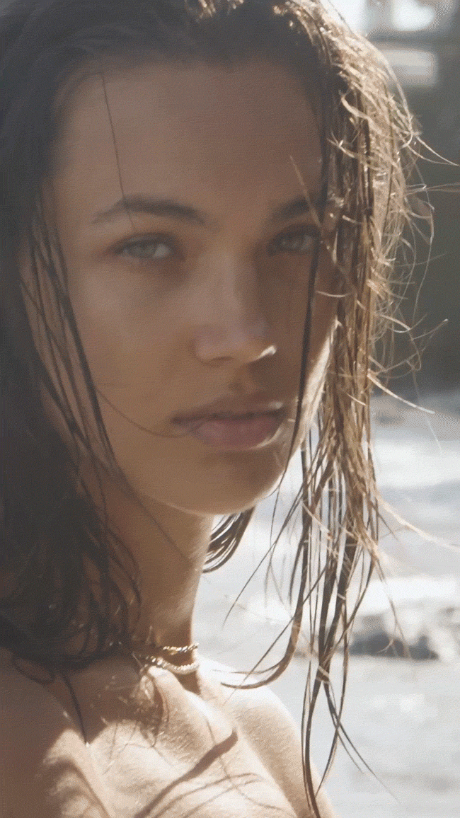 GIF of model at the beach wearing summer collection necklaces.