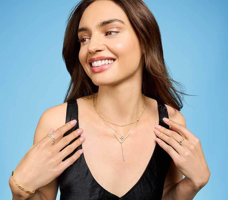 Model layered in dainty gold necklaces with diamond  details & pendants, with matching rings & bracelets.