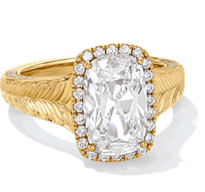 Yellow gold elongated cushion-cut diamond ring with halo and engraved band featuring leaf-like detailing.