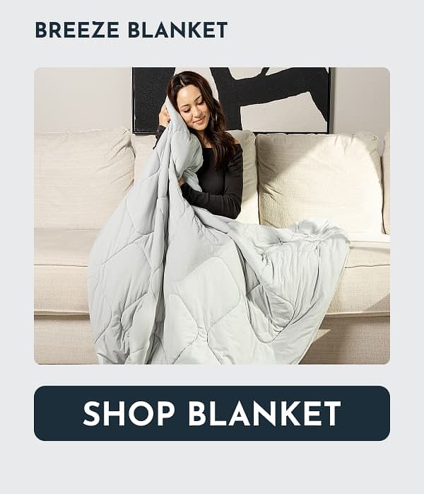 A woman sitting on a couch, holding a light gray blanket.