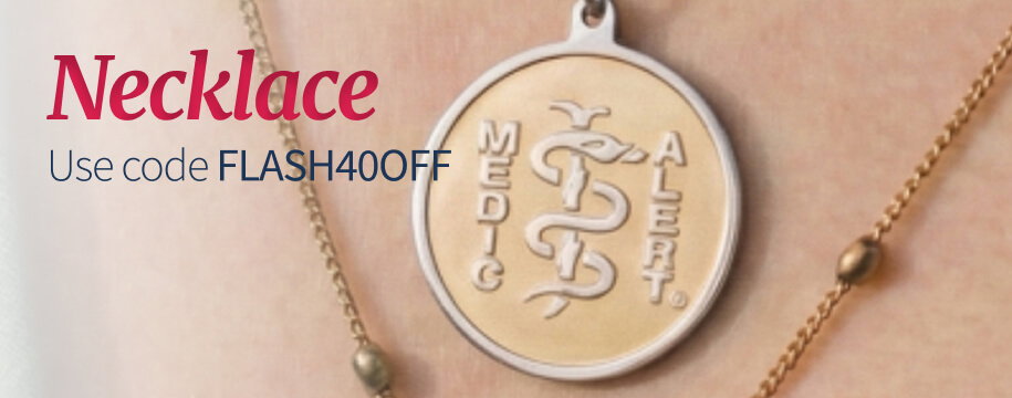 Close-up on a person's neck and upper chest, showcasing layered gold necklaces with integrated beads. Prominently featured is a silver and gold circular medical ID pendant with an engraved Caduceus. Dark red text on a faint gray overlay reads 'Necklace. Use code FLASH40OFF'.