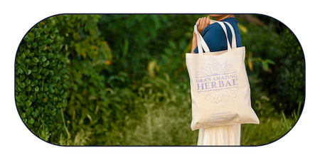 Image of an Ora canvas tote bag being carried outdoors in a grassy setting.