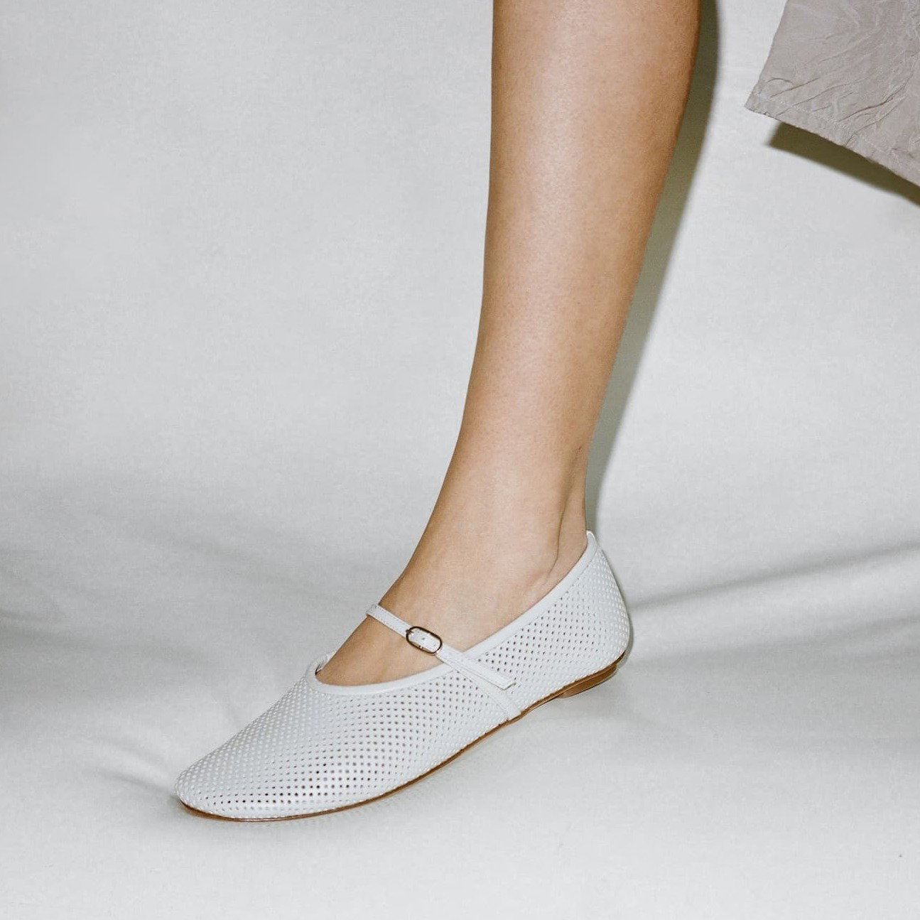 Person wearing white Mary Janes with perforated texture