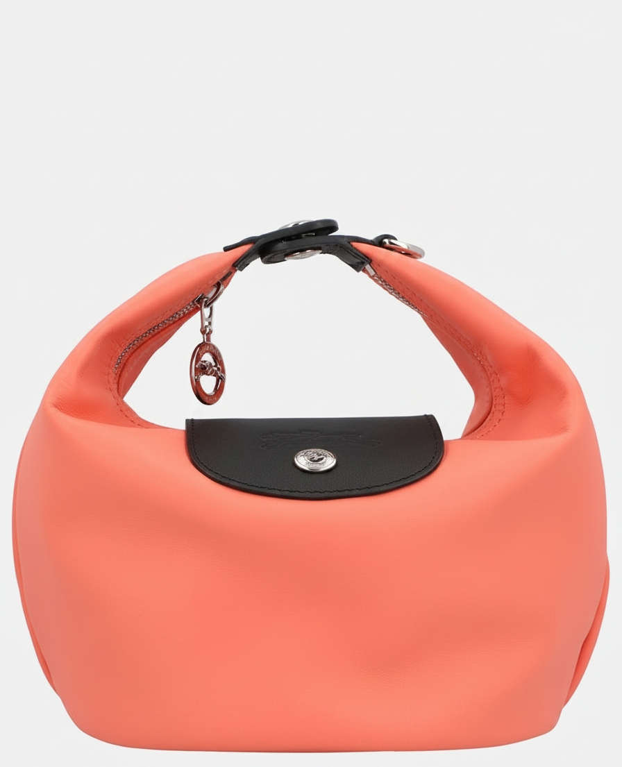 A coral-colored handbag with a black flap and silver hardware.