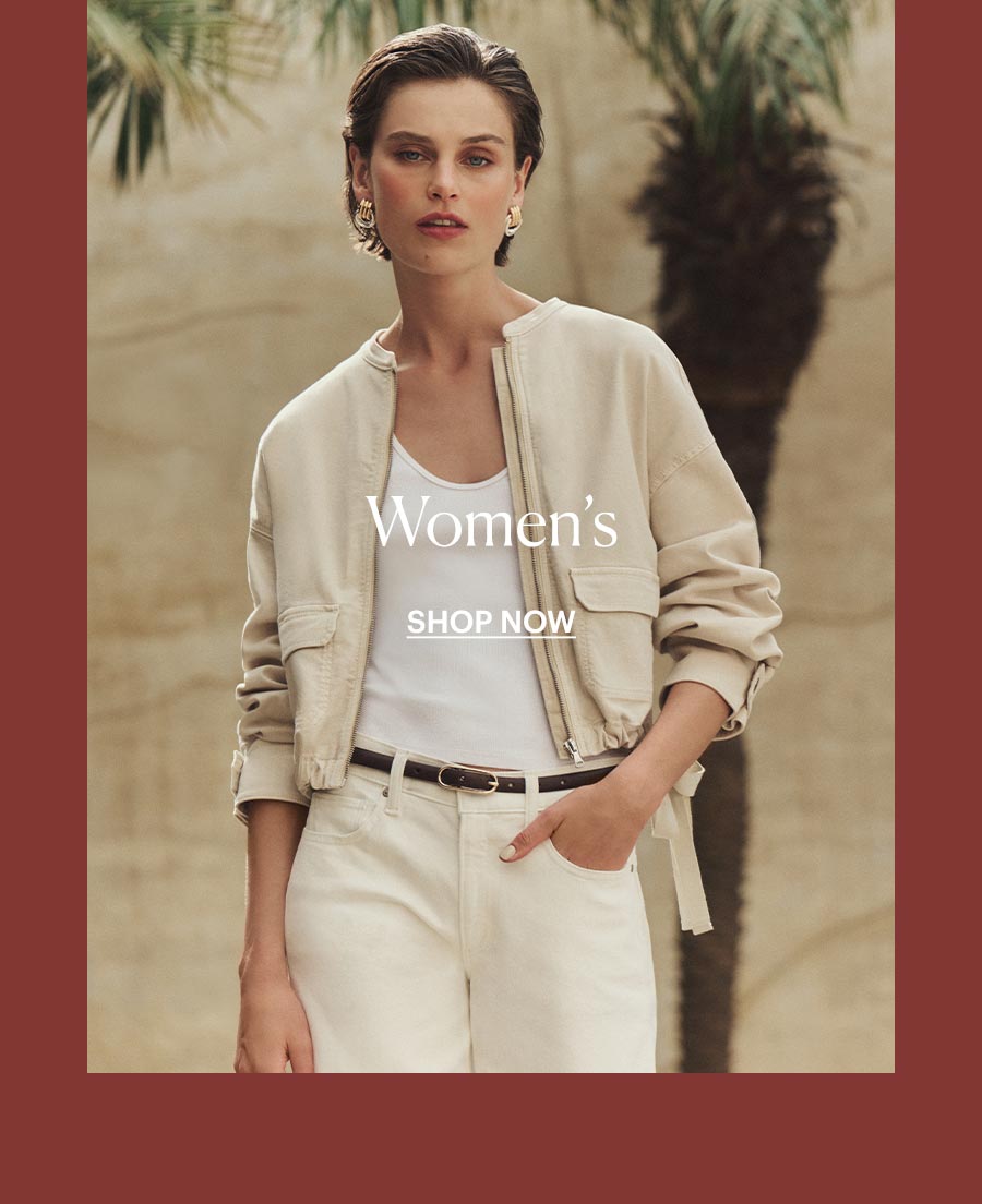 Shop The Women's Collection - Featuring an image of a woman wearing a cream colored jacket, white tank, light cream colored denim jeans and thin black leather with a background of beige textured wall and palm trees.