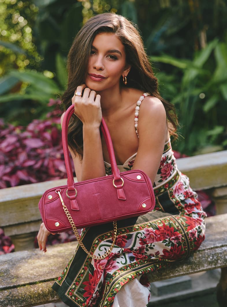Model in park holding Meredith Sml in calypso sueded brushed gold. 