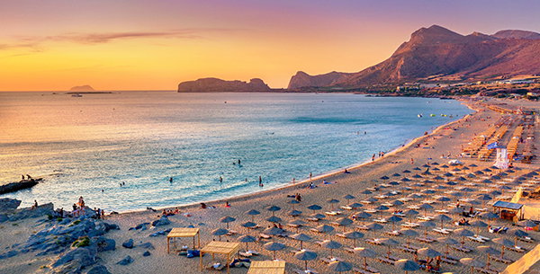 Belebter Strand in Griechenland bei Sonnenuntergang.