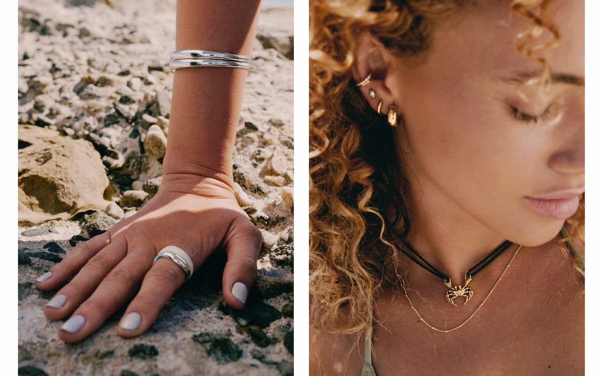 Left Image: Close-up of a silver cuff bracelet and stacked silver rings on a hand resting on rocky sand. Right Image: Close-up of a woman wearing gold stacked earrings and a gold crab charm necklace on a cord.