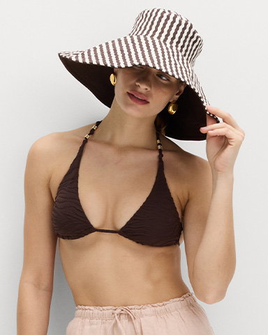 Woman wearing Pure Cotton Reversible Wide Brim Bucket Hat in Cream Mix with a Brown Bikini Top