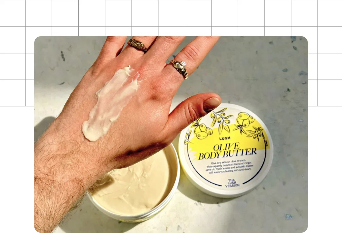 Jonnies hand with a swatch of Olive Body Butter and the pot in the background