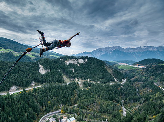 Eine Person springt einen Bungee Jump von einer Brücke.