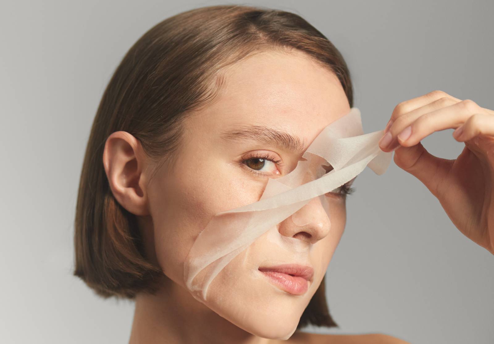 Woman pulling a sheet mask off of her face
