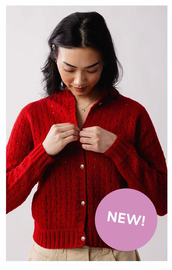 Image: A model is wearing a red knit cardigan with eyelet details. Text: NEW! >>