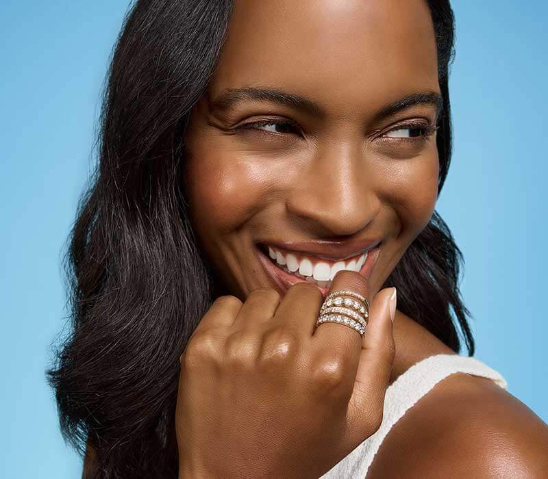 Model’s hand, focus on mixed-metal eternity bands, comprised of different sized round stones.