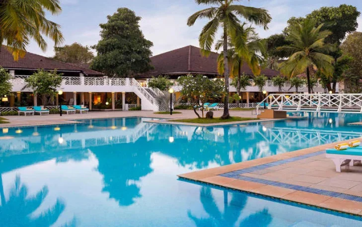 Perfect holiday resort with swimming pool surrounded by palm trees and deck chairs.