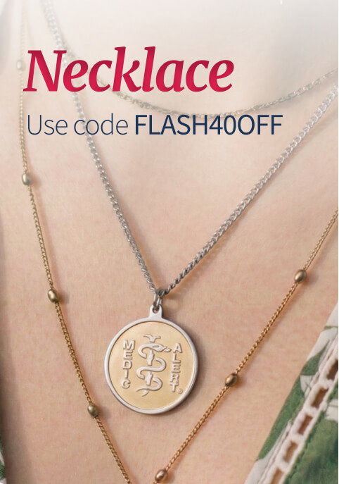 Close-up on a person's neck and upper chest, showcasing layered gold necklaces with integrated beads. Prominently featured is a silver and gold circular medical ID pendant with an engraved Caduceus. Dark red text on a faint gray overlay reads 'Necklace. Use code FLASH40OFF'.