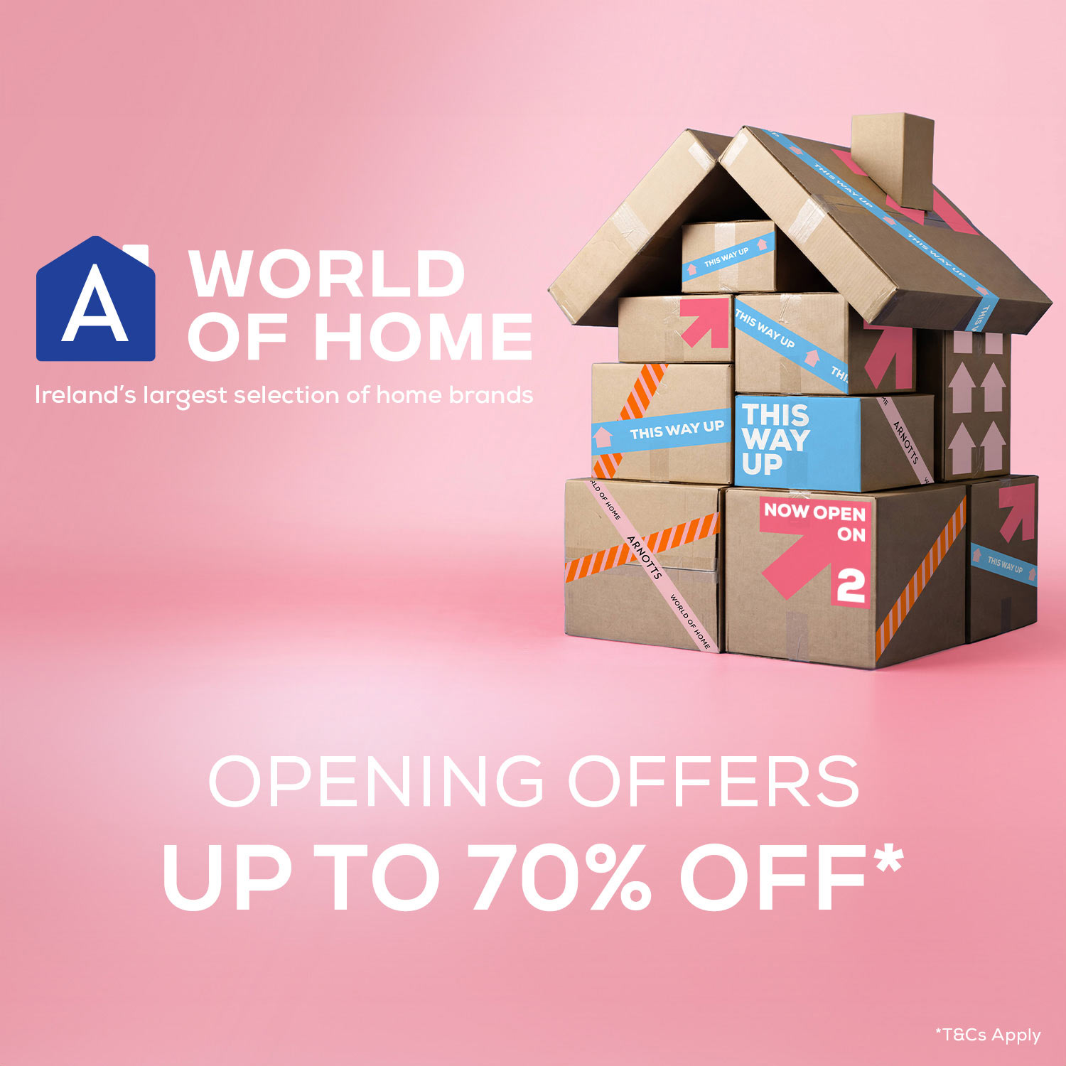 Cardboard boxes arranged to form a house, with labels like 'This Way Up' and 'Now Open'. Text reads 'A World of Home: Ireland's largest selection of home brands. Opening offers up to 70% off.' Background is pink.