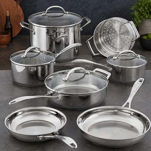 Stainless steel cookware set including various sized saucepans with lids, a stockpot, a skillet, and a steamer insert, all arranged on a dark kitchen countertop.