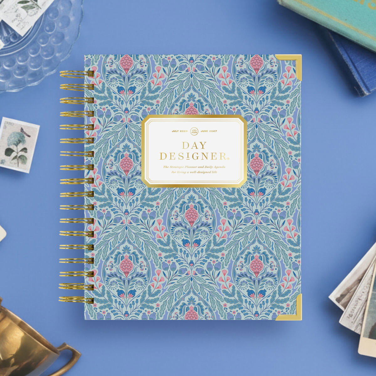 repeated blue and pink ornamental medallions and scrollwork, gold binding, day designer logo, blue background, glass plate, brass trophy, stamp, postcards