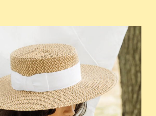A woman wearing a straw hat with a white ribbon, partially visible against a light background.