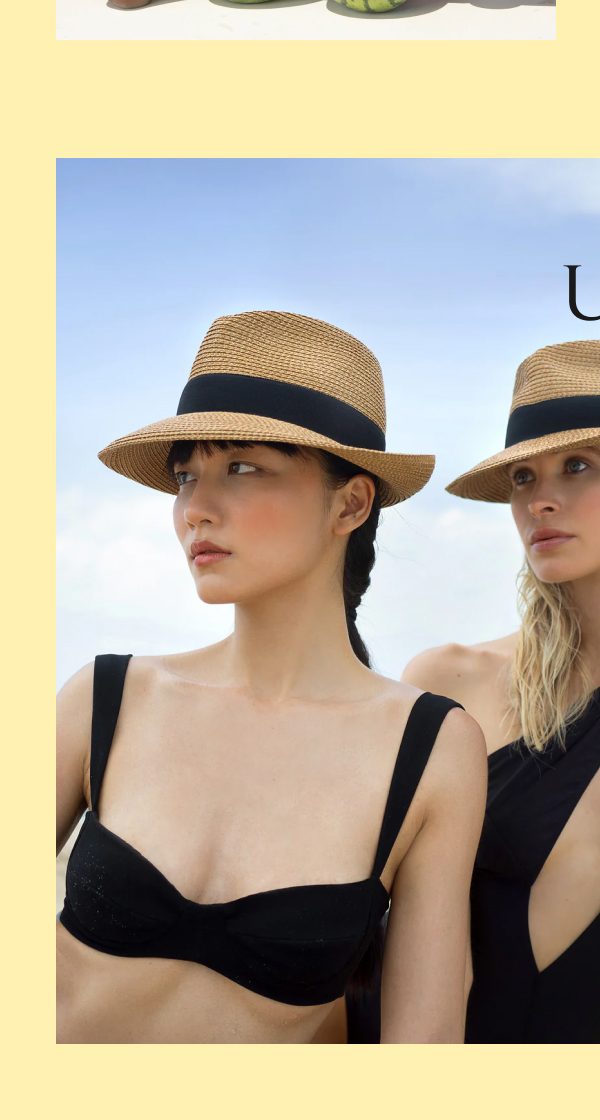 Two women wearing hats and swimwear, standing on a beach.