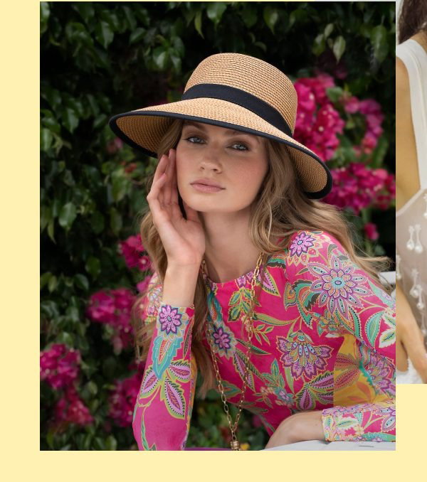 A woman in a colorful dress and straw hat poses against flowers and a beach backdrop.