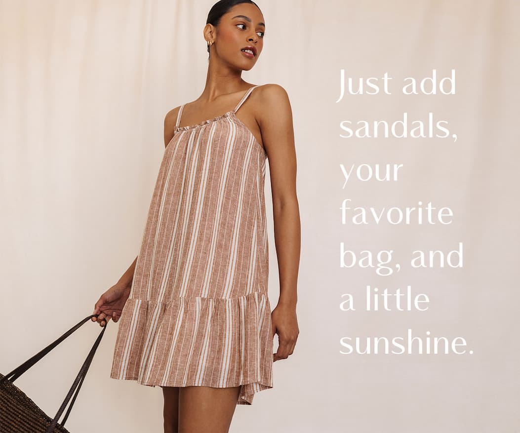 Model wearing a striped sleeveless summer dress while holding a woven bag, with overlay text about effortless warm-weather styling.