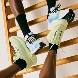 Dos personas que llevan zapatillas deportivas y calcetines negros interactuando con una escalera de madera contra una pared blanca lisa.