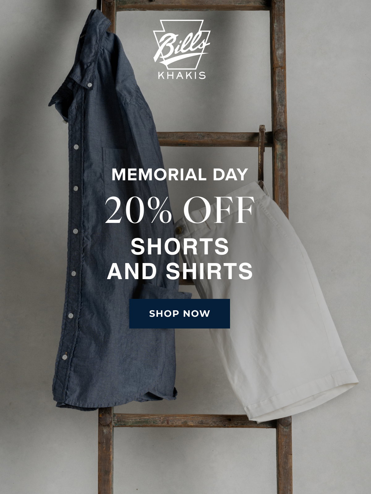 A background photo shows a Bills Khaki shirt and pair of shorts hanging from a vintage wood ladder. The Bills Khakis logo overlays the photo with text that reads: Memorial Day | 20% Off | Shorts and Shirts | Shop Now