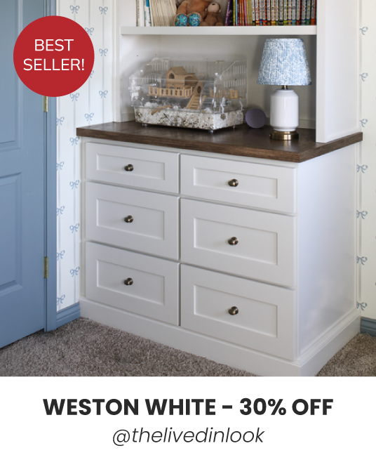 White dresser with six drawers, lamp, books, toys.