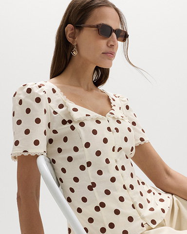 Woman sitting wearing Polka Dot Lace Detail Button Through Top in Ivory Mix