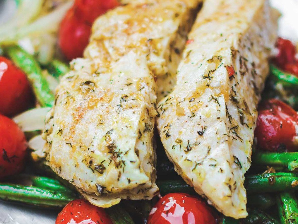A serving of baked halibut with vegetables on a plate.