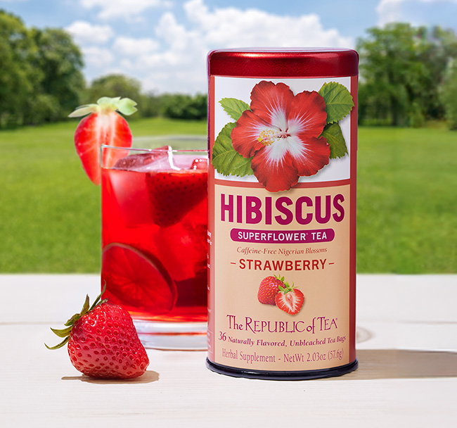 Hibiscus Strawberry tin with mocktail next to tin in outdoor environment