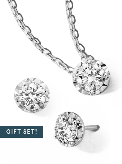 Diamond solitaire necklace with matching stud earrings displayed as a gift set.