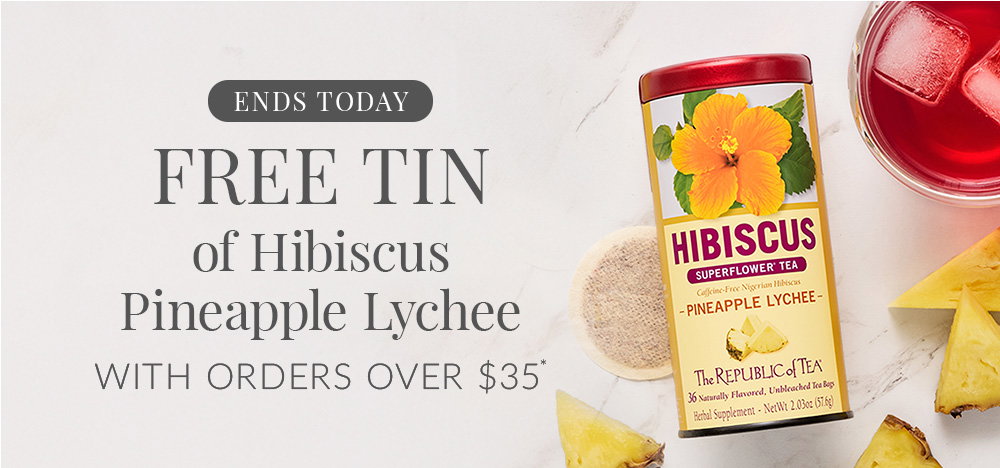Tin of Hibiscus Pineapple Lychee tea with a teacup of next to tin with ice and pineapple pieces surrounding tin