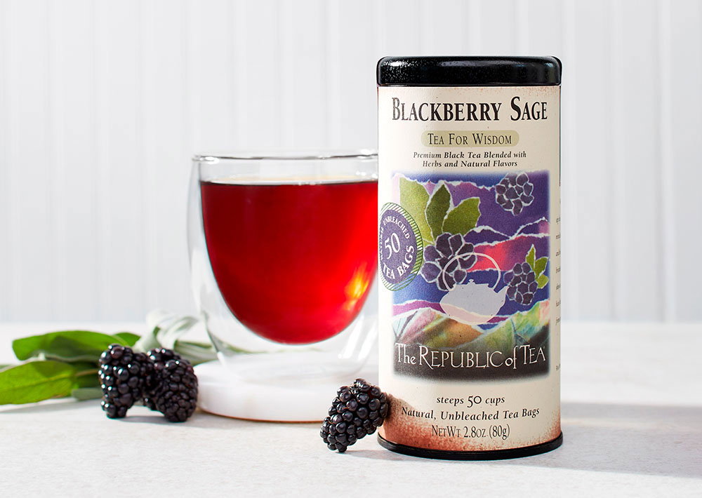 Blackberry Sage tin with teacup next to tin and blackberries on surface