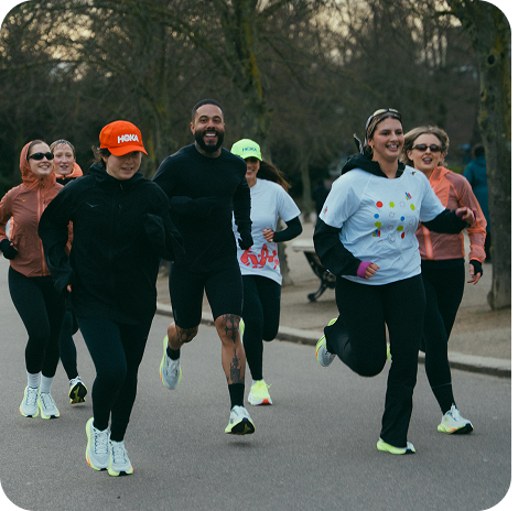 Group of people running in a park and smiling.