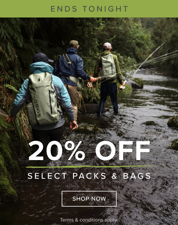 3 individuals wading through the shallow edge of a river wearing wading gear and Orvis backpacks while find an area to fish