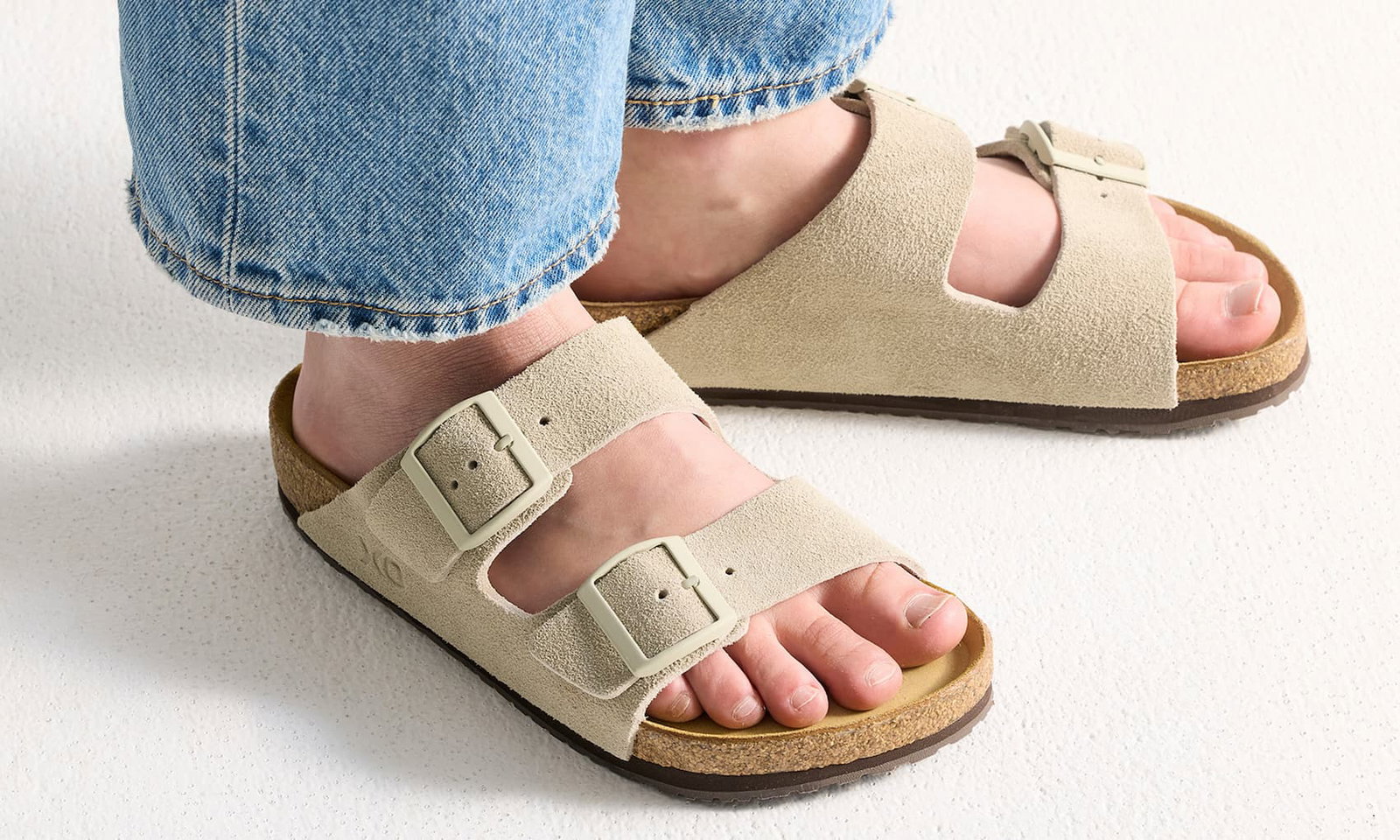 Person som bär sandaler i mjuk mocka i ljusbeige färg