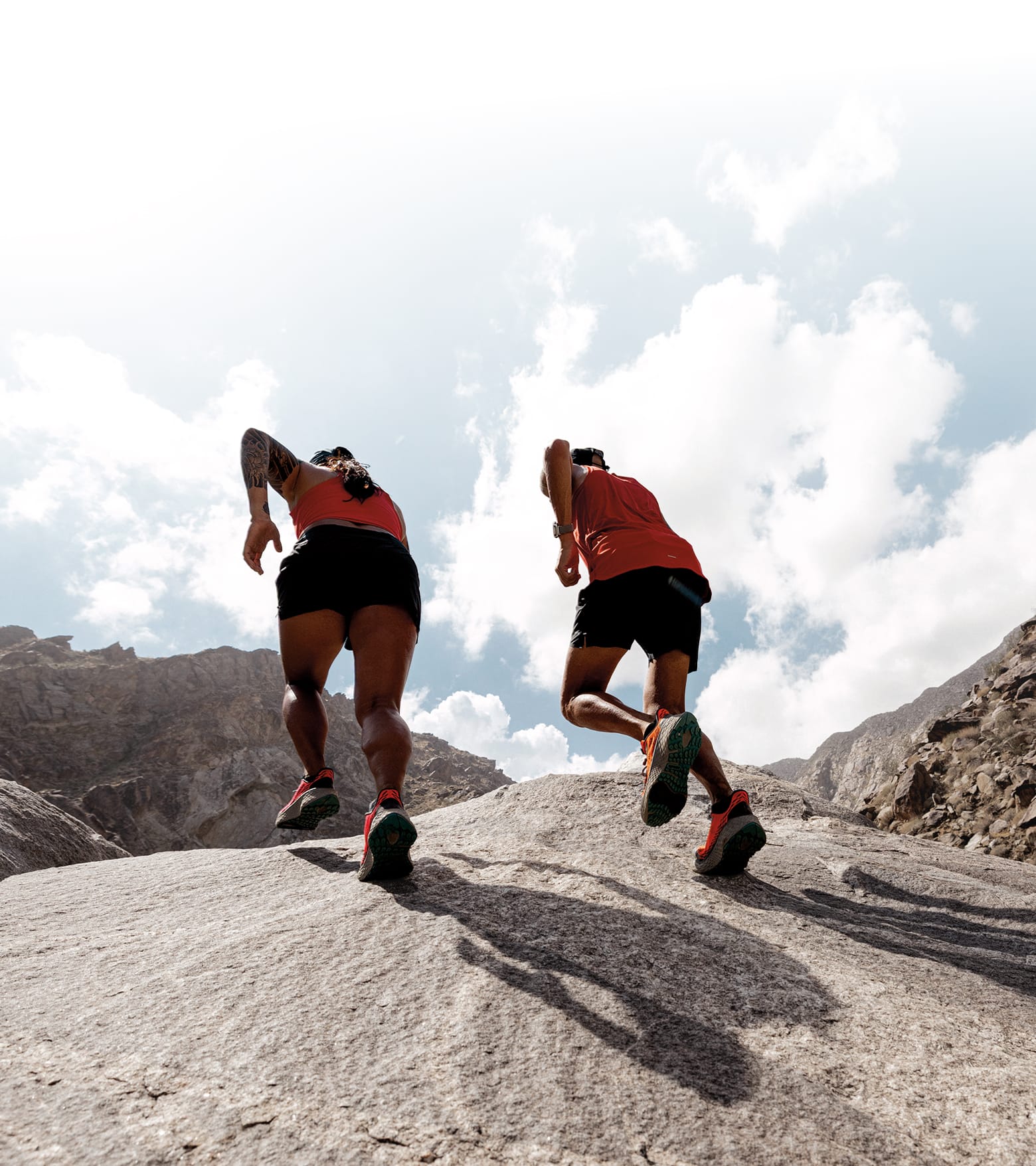 Man and woman running up a steep rocky incline.