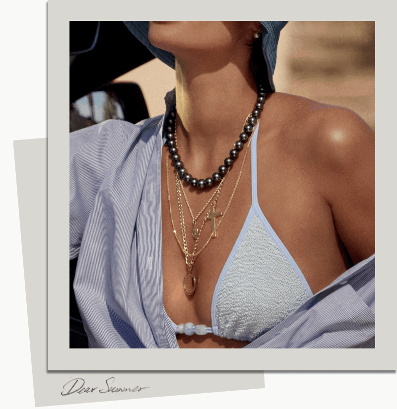 Model wearing layered necklaces over a bikini top. 