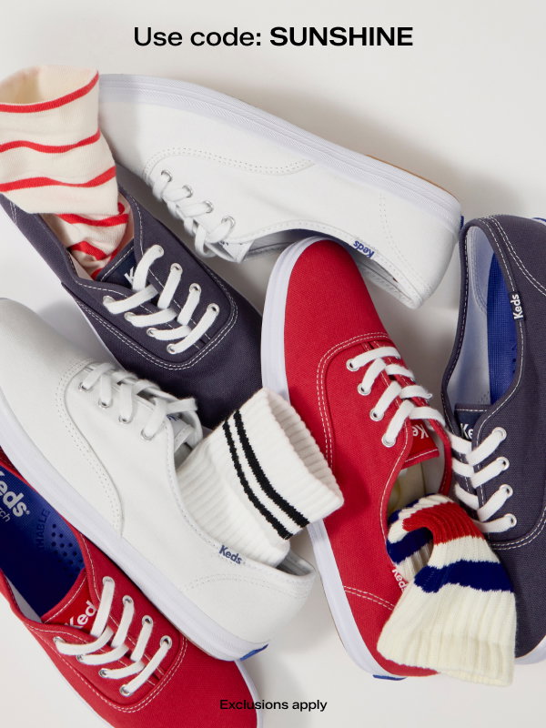 A light gray background with group of Keds Champion lace-ups in white, red, and navy canvas are shown from a top-down view, some styled with striped socks.